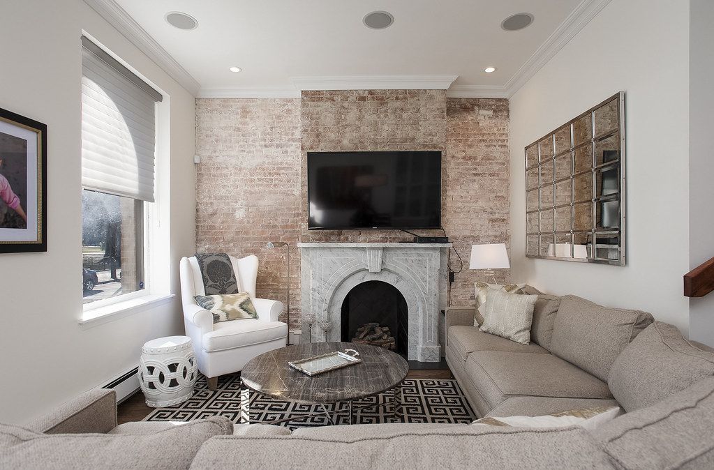 Living room with exposed brick and a white fireplace