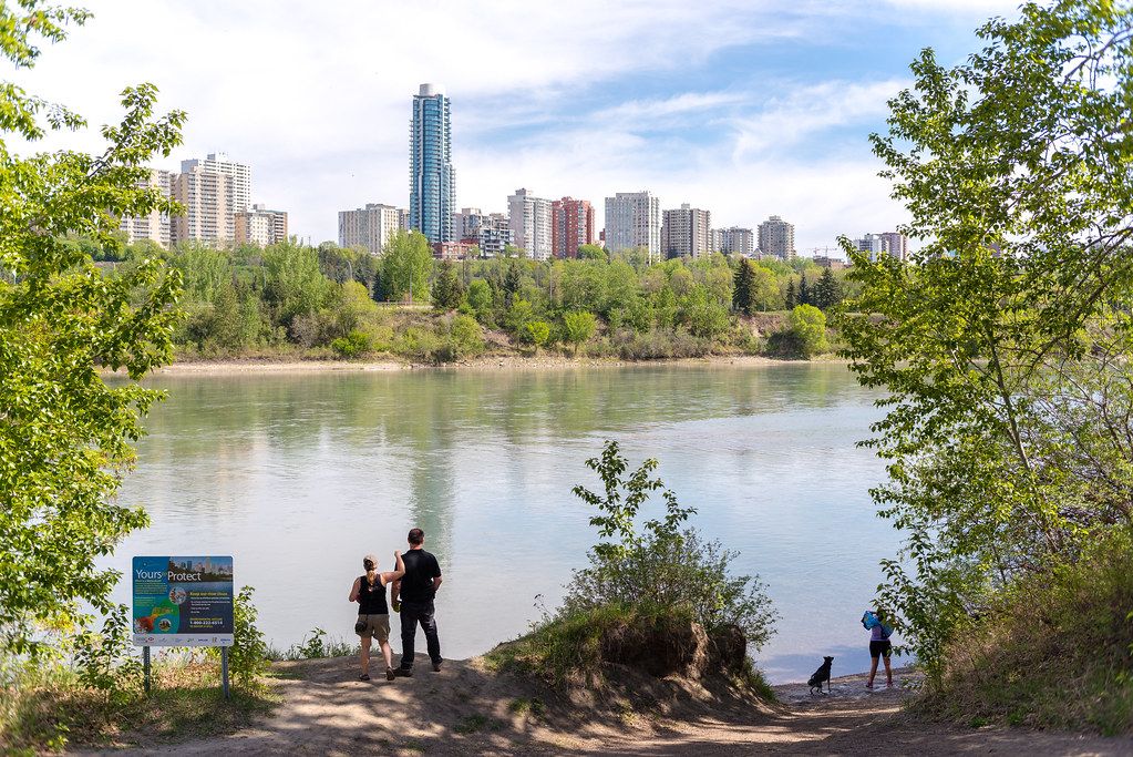 People on the bank of the North Saskatchewan River with the Edmonton skyline behind